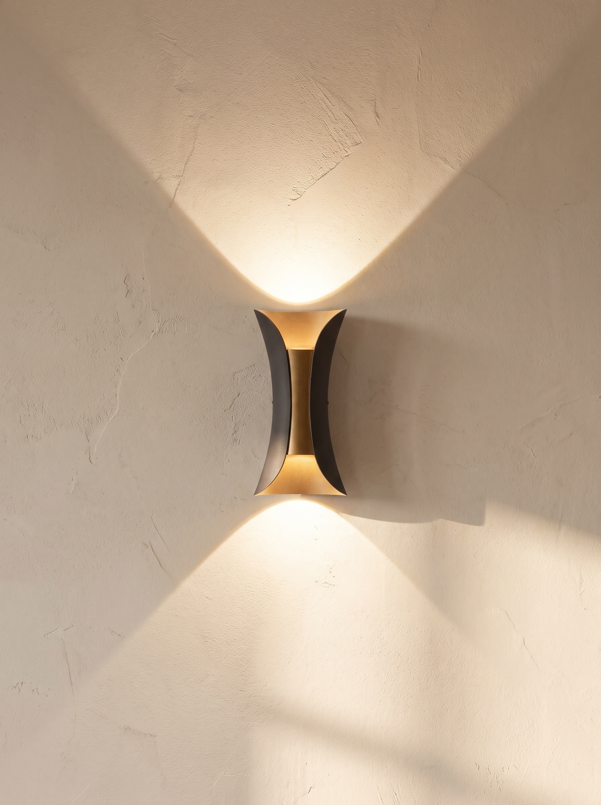 Arcelle sconce throwing two cones of warm light up and down a wall