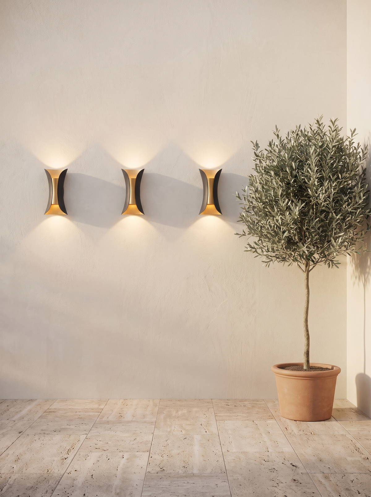 Three Arcelle sconces in a row along a cream courtyard wall